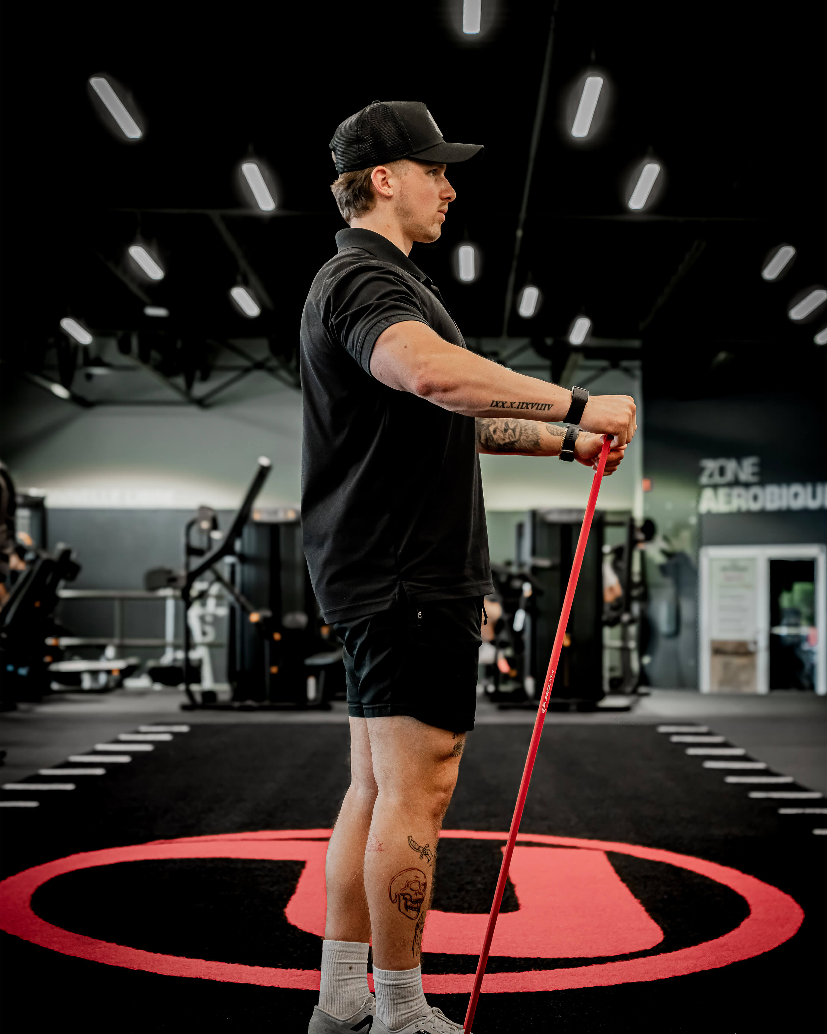 Entraîneur ProGym utilisant une bande de résistance rouge sur le tapis de la salle de sport