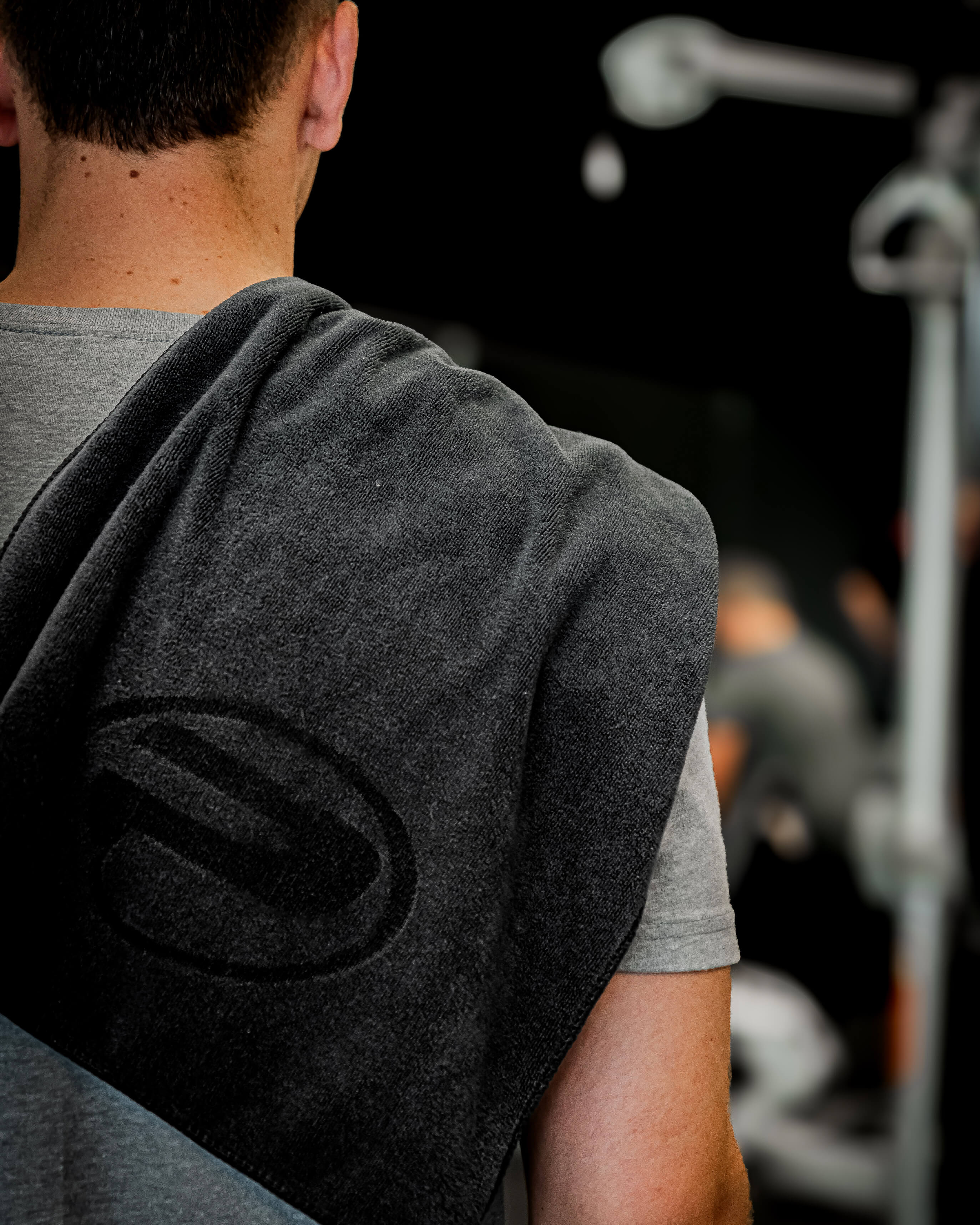 Serviette d’entraînement ProGym noire portée sur l’épaule d’un homme