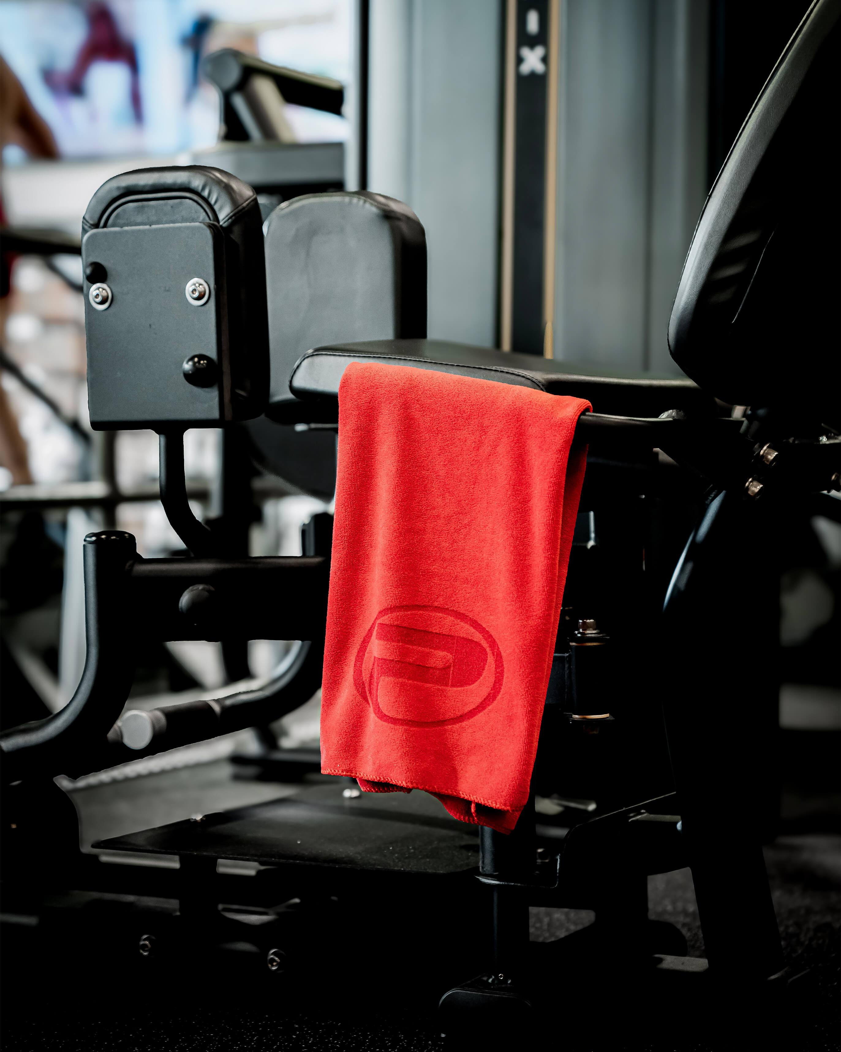 Serviette d’entraînement ProGym rouge accrochée à un appareil de musculation