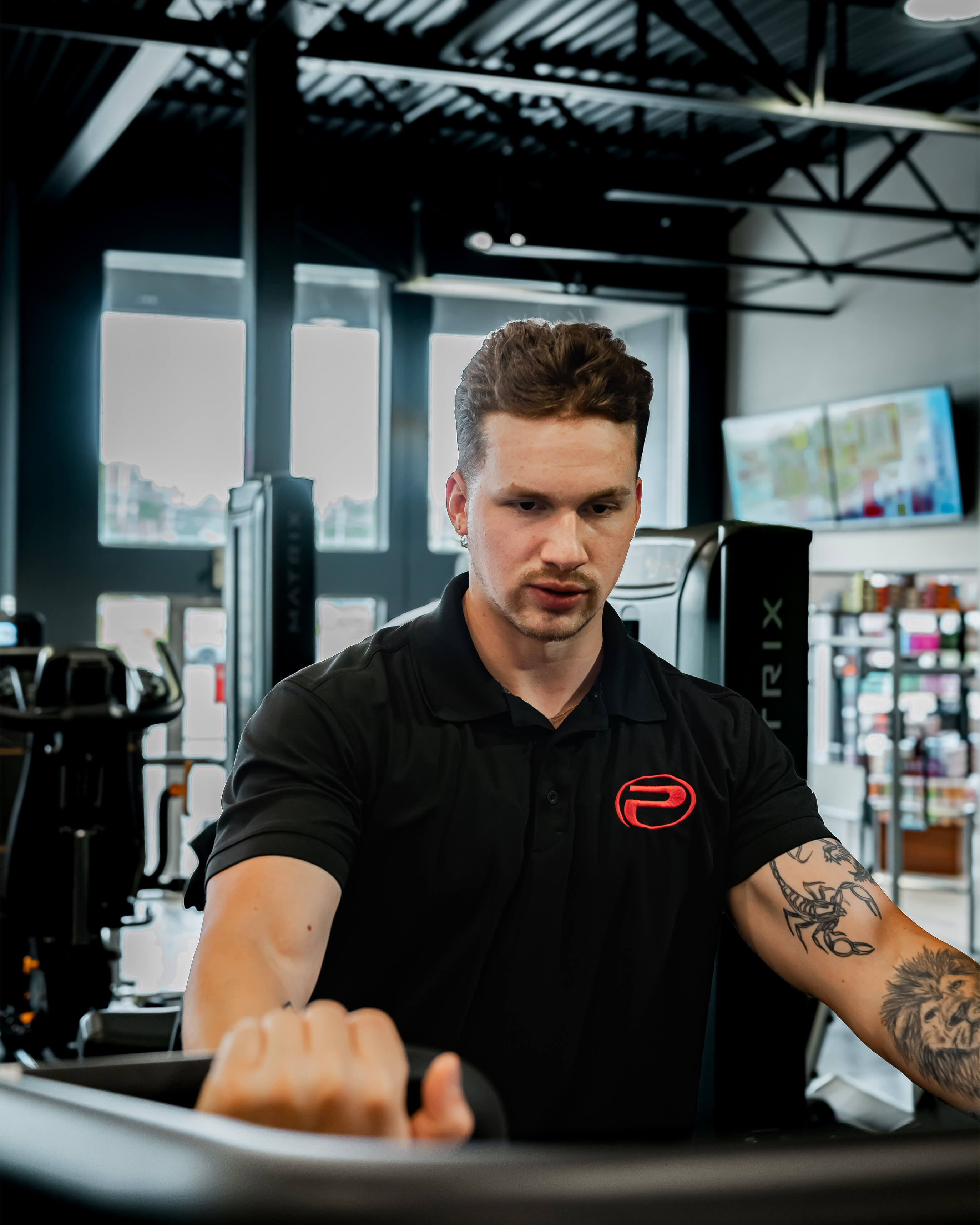 Polo noir ProGym avec logo rouge porté par un membre à la salle de sport