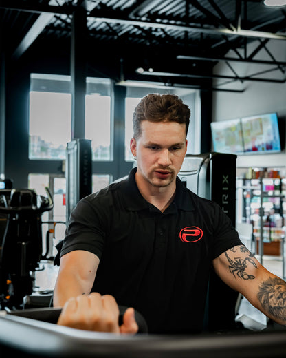 Polo noir ProGym avec logo rouge porté par un membre à la salle de sport