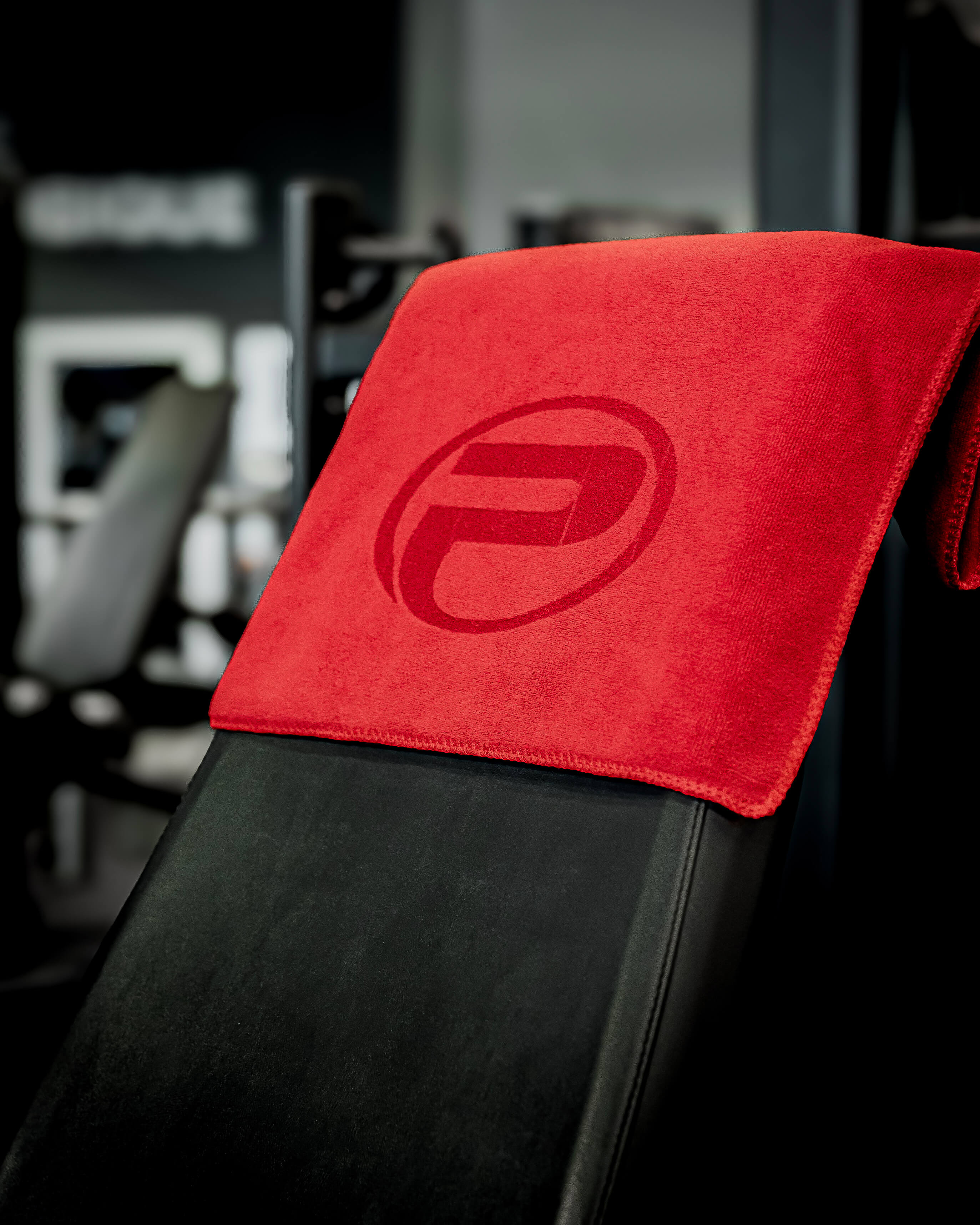 Serviette d’entraînement ProGym rouge posée sur un banc de musculation