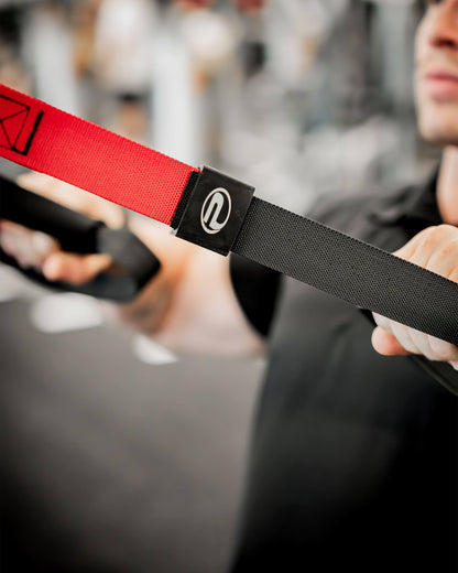 Gros plan sur les sangles d’entraînement en suspension TRX ProGym rouge et noir utilisées à la salle de sport