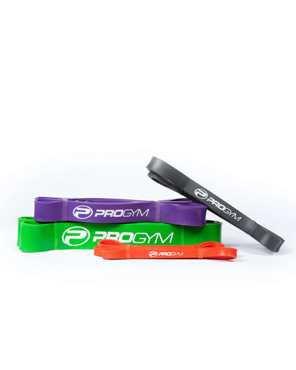 Ensemble de quatre bandes de résistance ProGym empilées, de couleurs rouge, noire, mauve et verte, chacune portant le logo et le nom « PROGYM » en blanc.